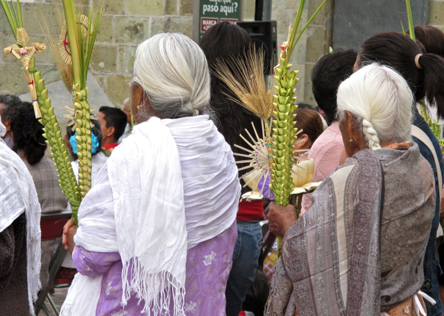 2 women wearing rebozos, with their palms.
