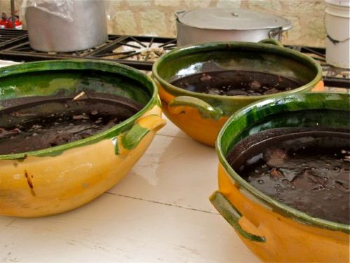 Large green pottery bowls filled with black mole. 