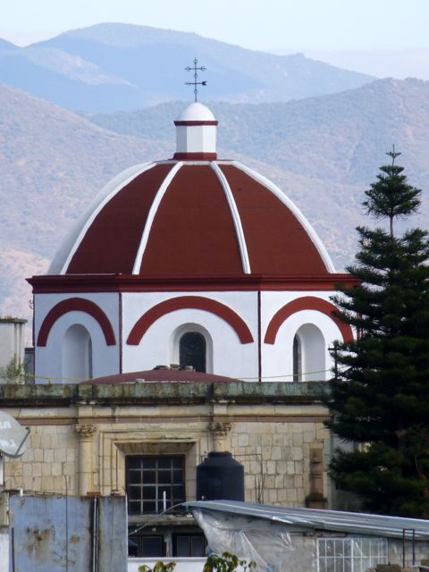 Red dome of church in foreground with mountains in background