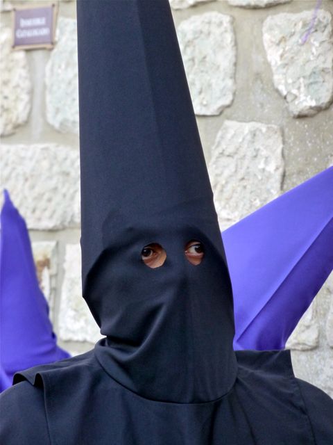 Purple hoods behind black hooded penitent